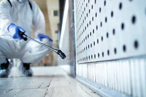 A person dressed in a white suit and gloves meticulously cleans a floor, ensuring a pristine environment.